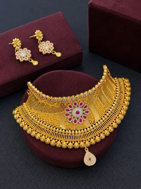Intricate gold necklace and matching earrings displayed on burgundy velvet